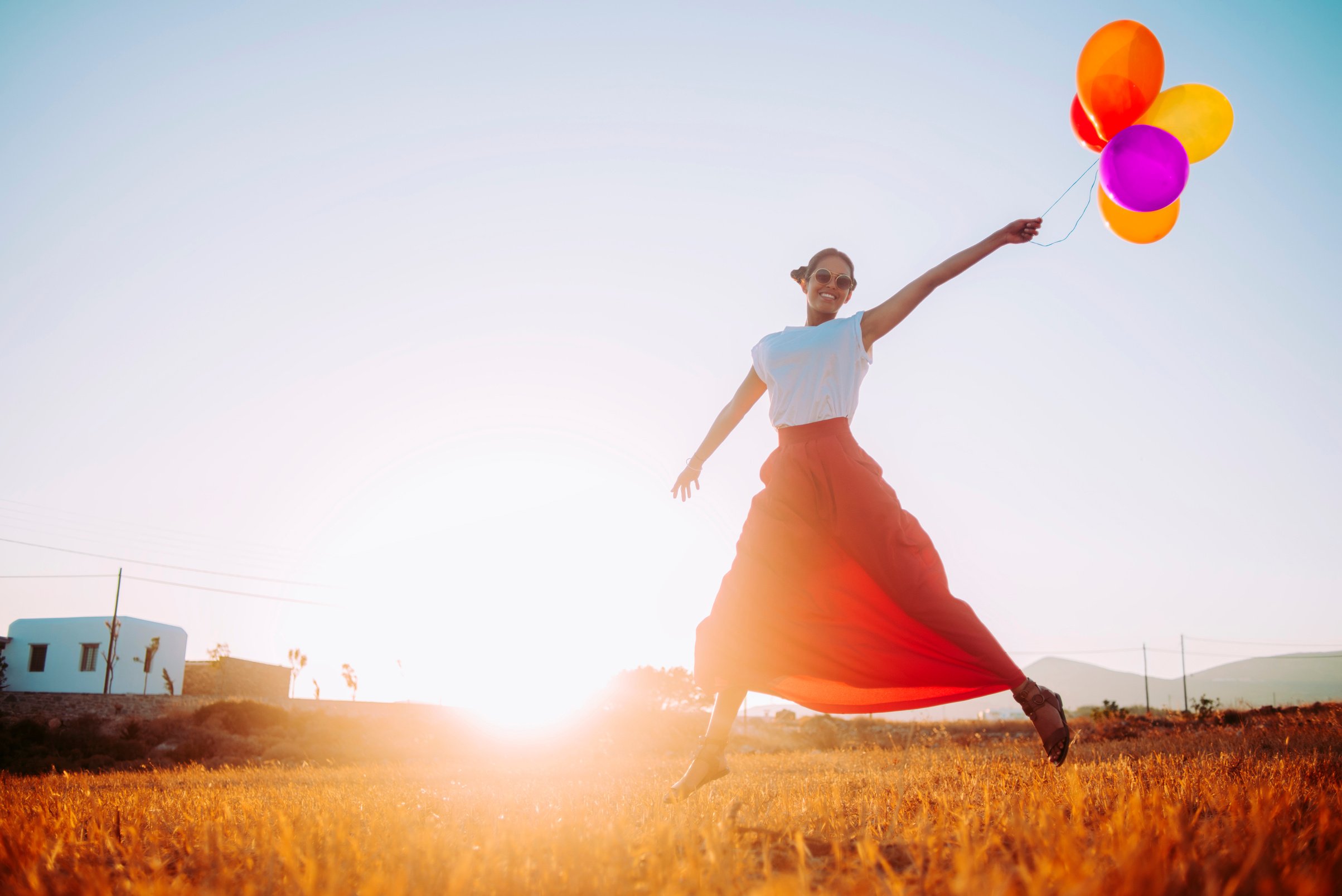 beautiful young woman running in the field with balloons